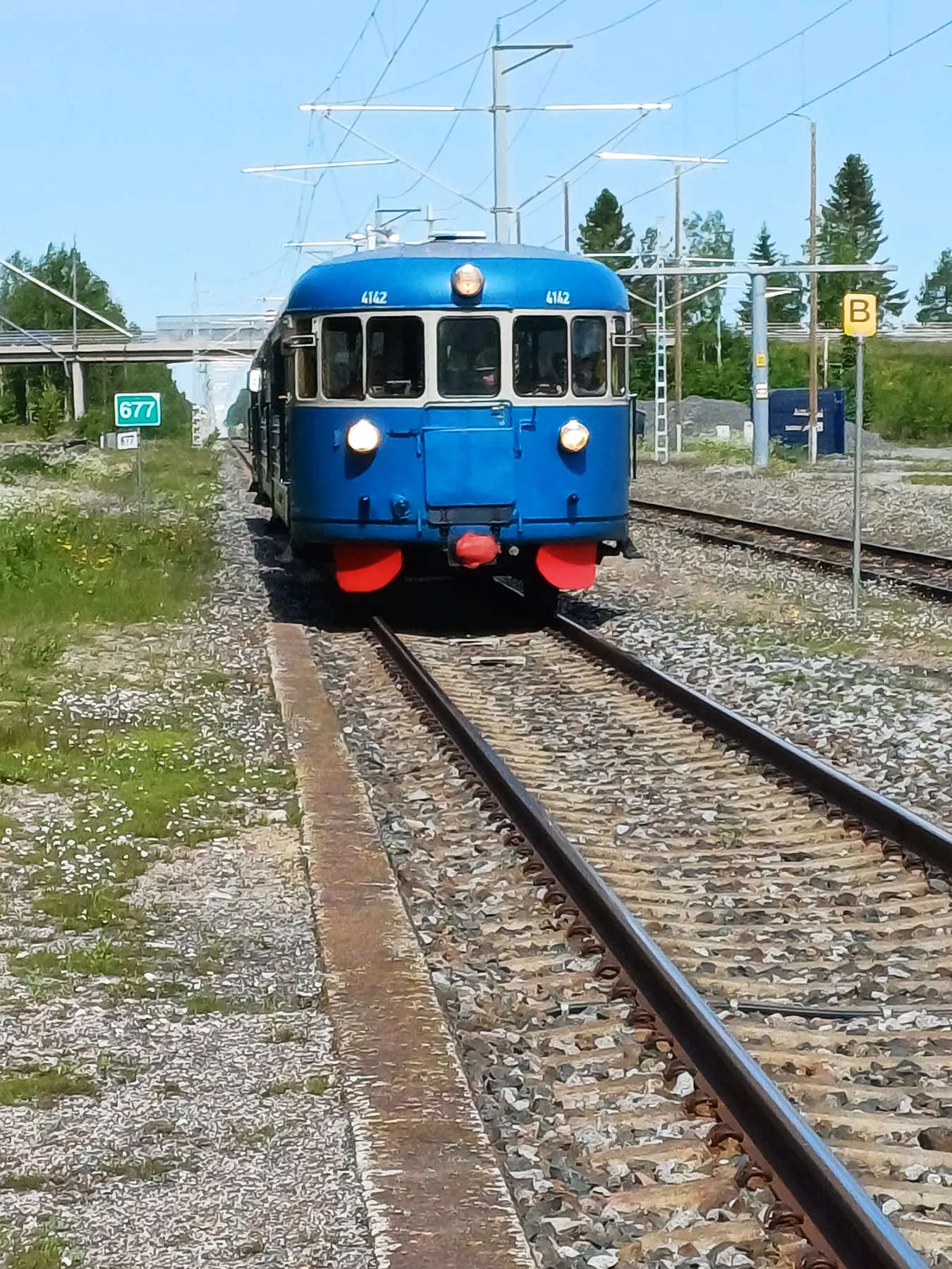 Vanha juna, sininen lättähattu, kulkee kiskoilla.